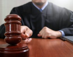 justice and law concept.Male judge in a courtroom striking the gavel,working with digital tablet computer docking keyboard on wood table